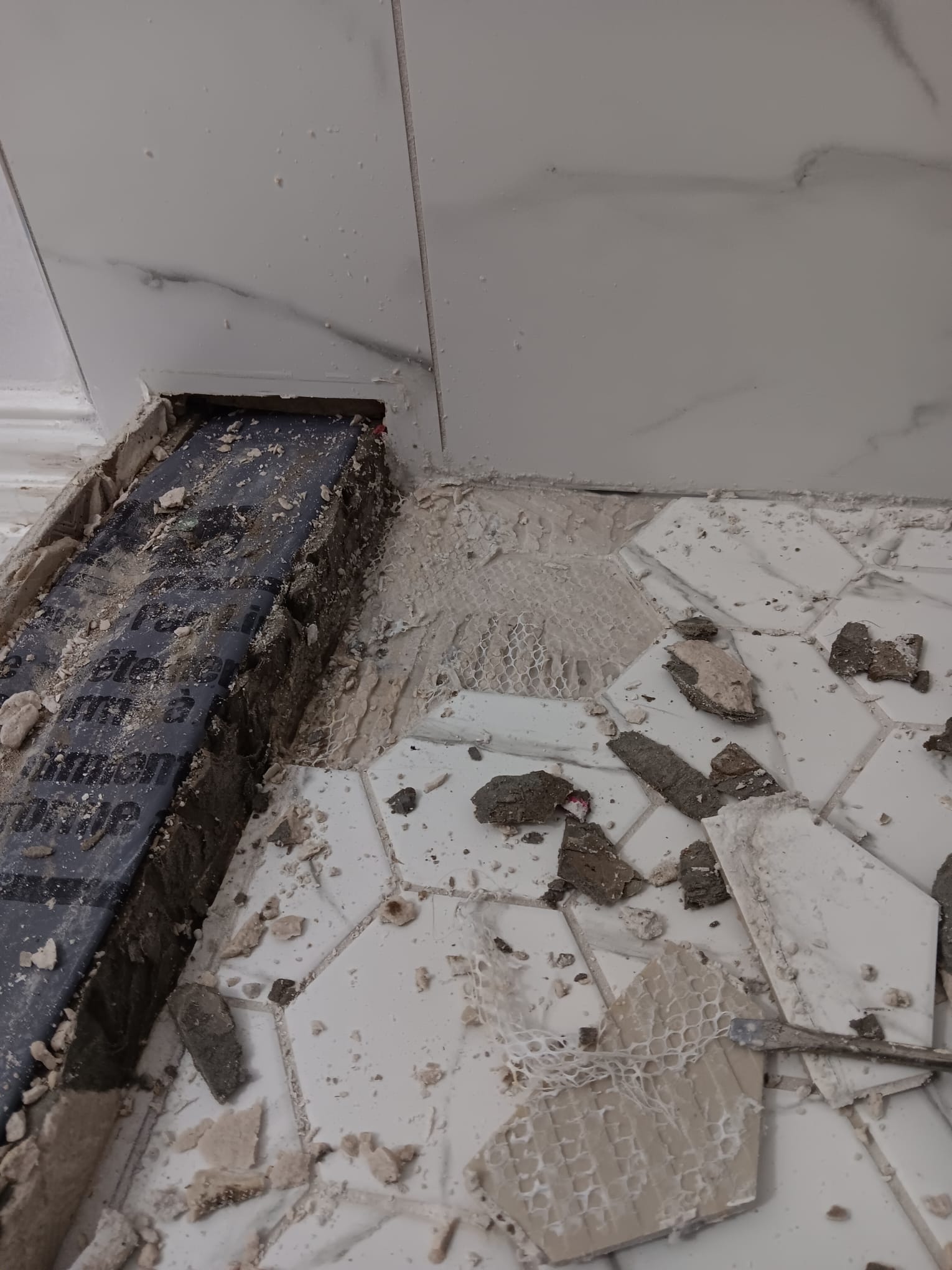 Severe water damage to shower curb showing rotted wood and failed materials from missing waterproofing membrane